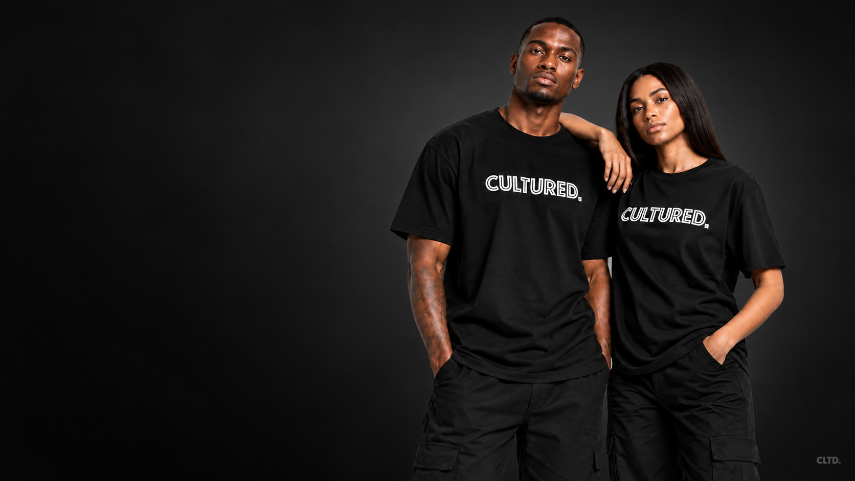 Two models wearing original black CULTURED. tees against a dark editorial background.