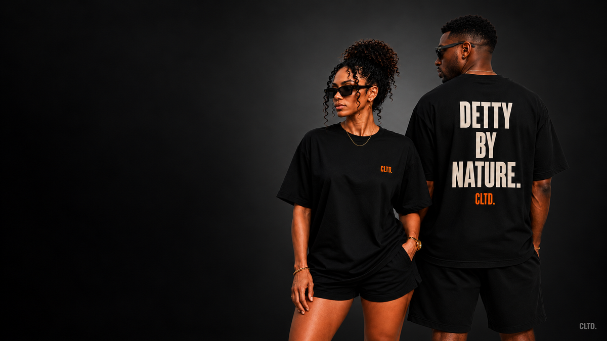 Two models showing the front CLTD. chest mark and DETTY BY NATURE back graphic on black tees against a dark charcoal backdrop.