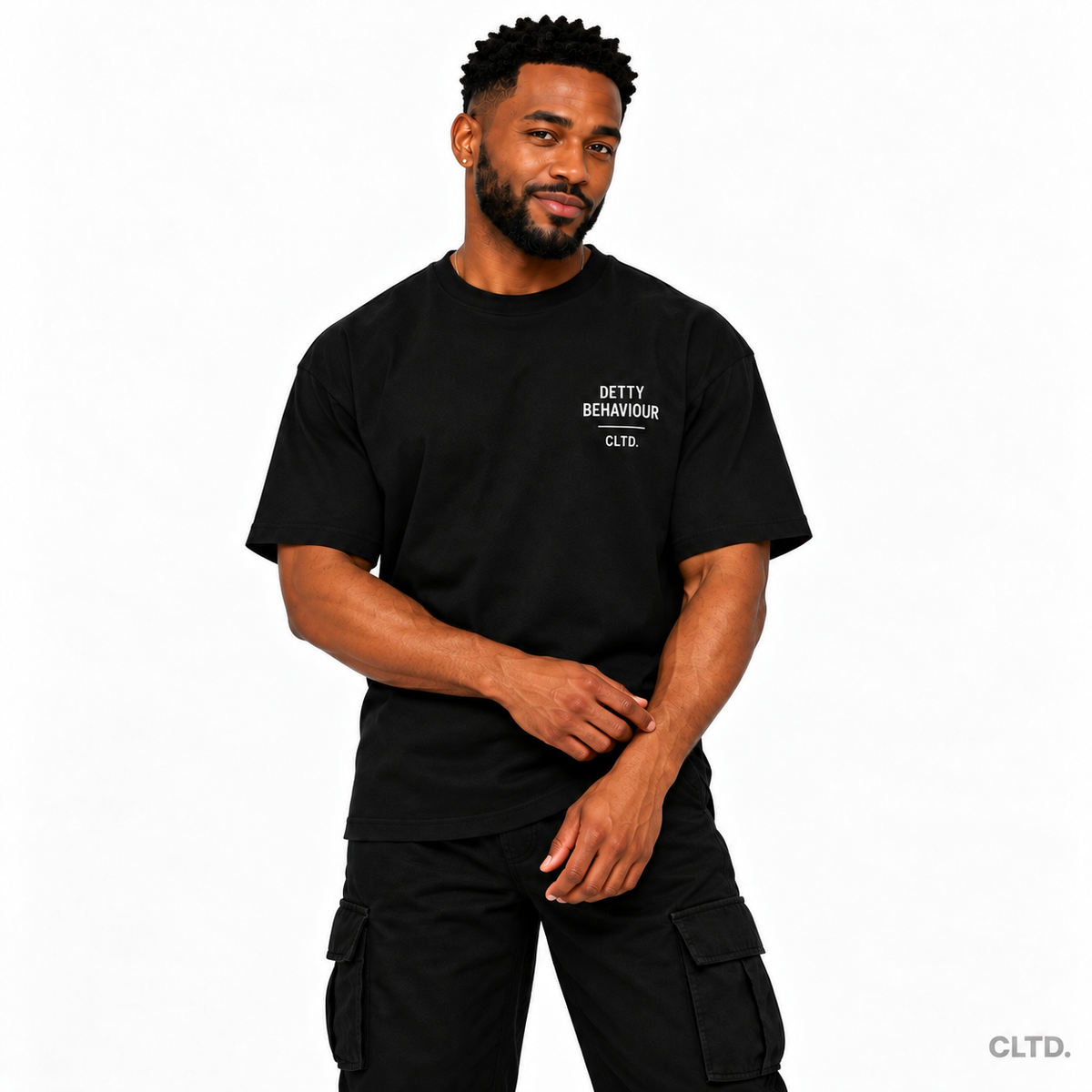 Detty Behaviour black T-shirt — male model front view with a subtle smirk